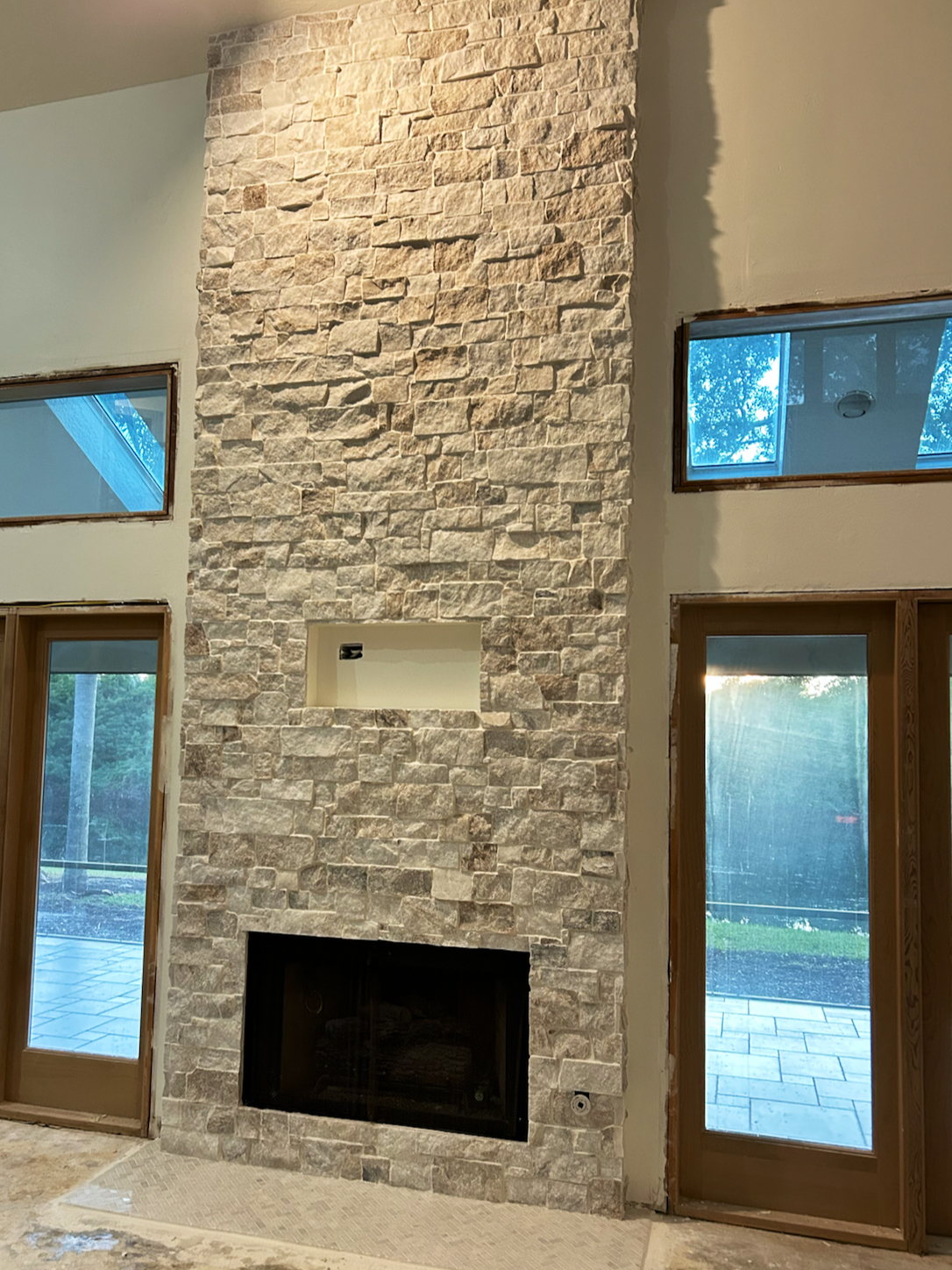 Floor-to-ceiling stacked stone fireplace by 321 Tile